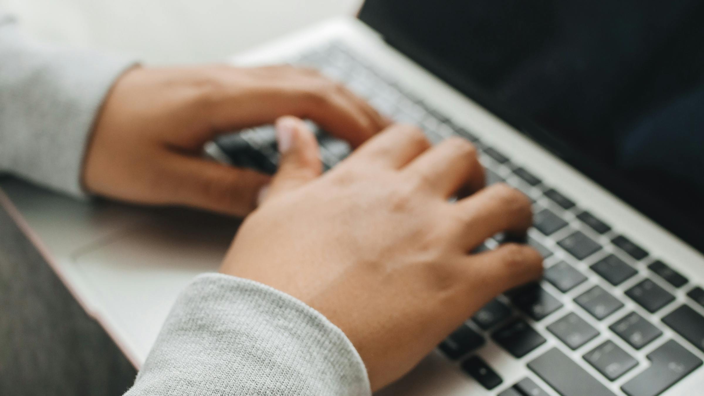 Hands typing on a laptop keyboard - digital accessibility and keyboard navigation