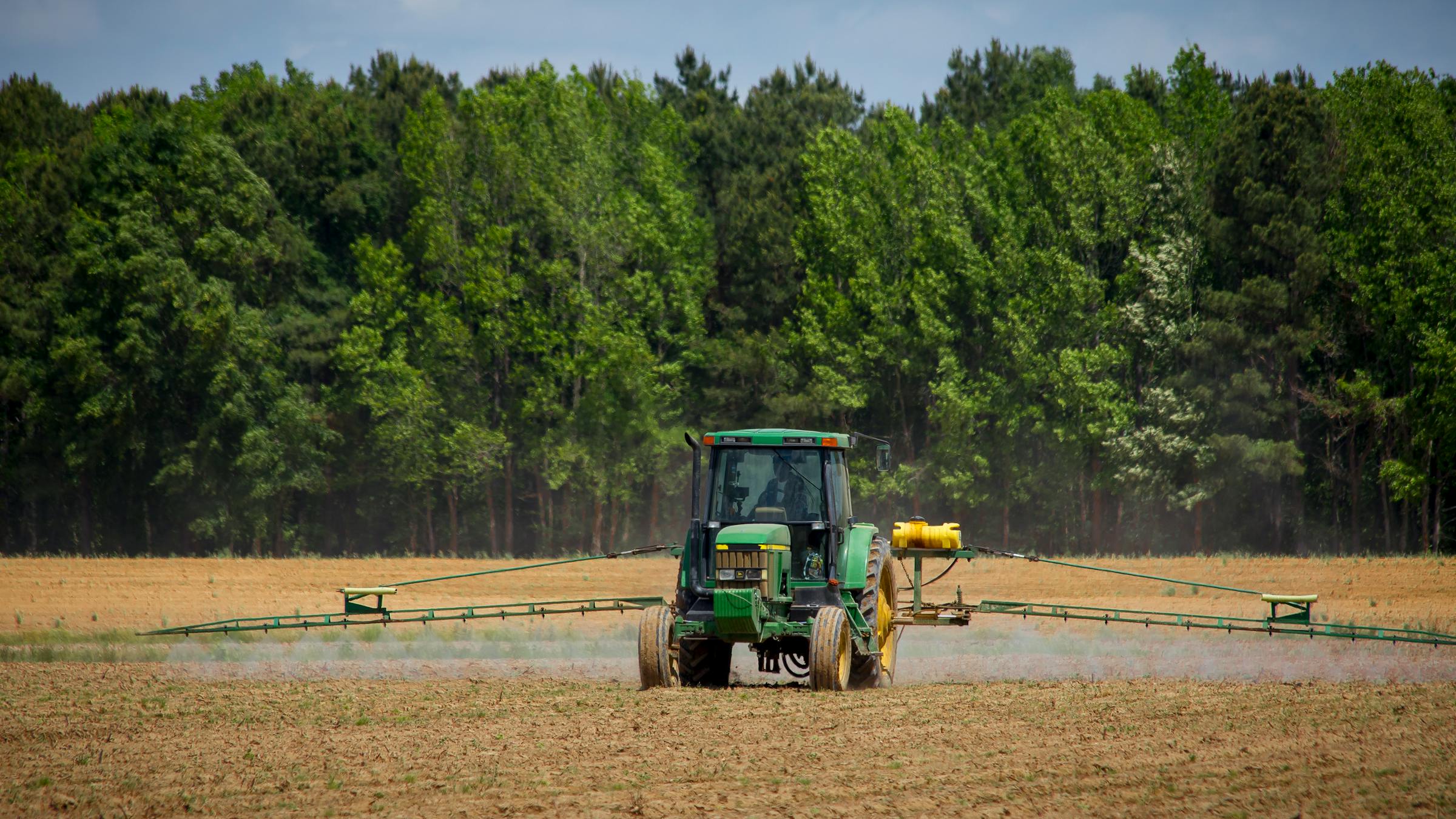 Tractor with a field sprayer applying plant protection products