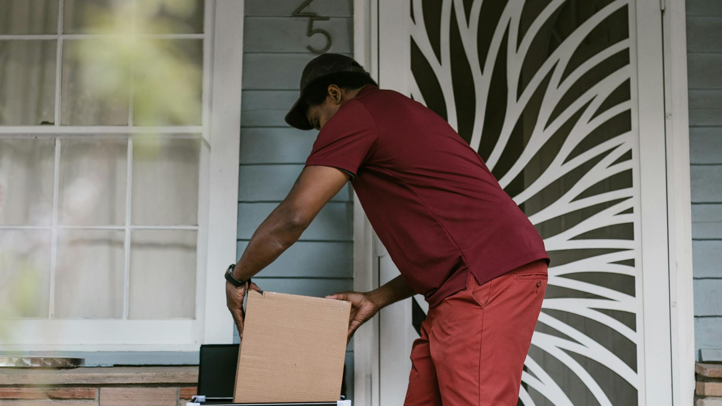 Courier picking up a cardboard package from a doorstep - e-commerce delivery and returns